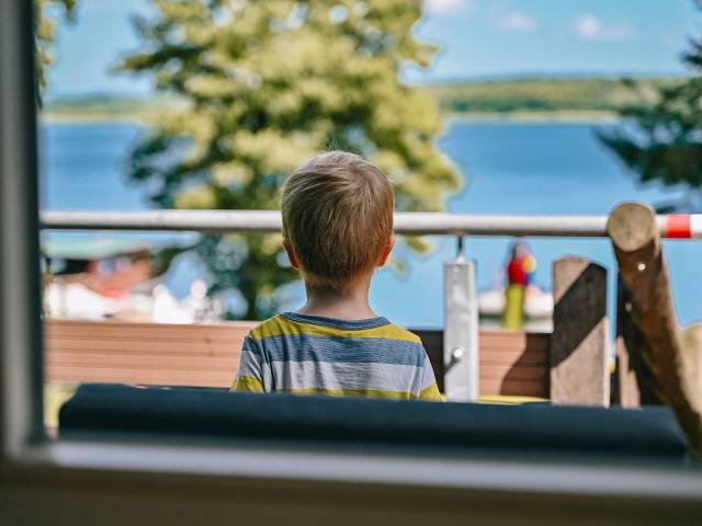 Kleiner Junge blickt auf dem Labussee auf der Terasse des Hotels