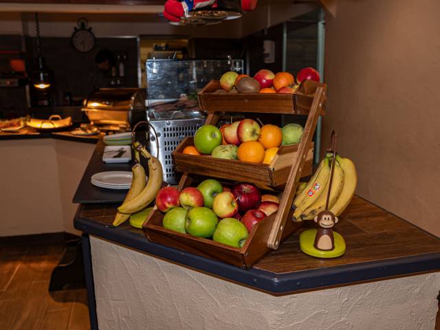 Eine Etagerie voller Obst und Bananenständer daneben am Frühstücksbuffet