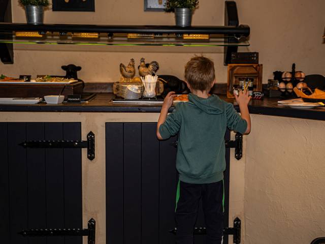 Ein Junge schaut am Frühstücksbuffet die Eier an