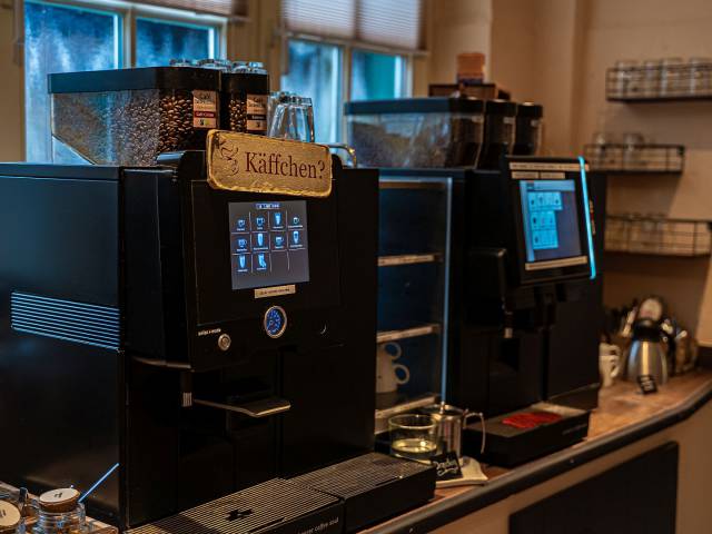 zwei Kaffeevollautomaten, auf dem einen ein Schild "Käffchen?"