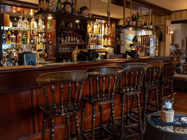 Hotelbar mit hohen Holzhockern und vielen Getrränken im alten englischen Stil
