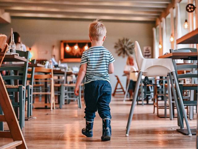 Kleiner Junge mit Gummistiefel läuft durch das Restaurant