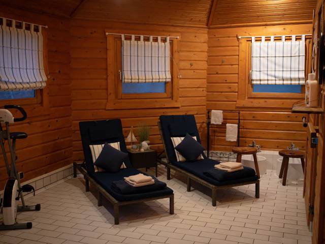 Zwei Liegen mit Handtüchern, Kissen und einem Laufrad in der Holzhütte der Sauna