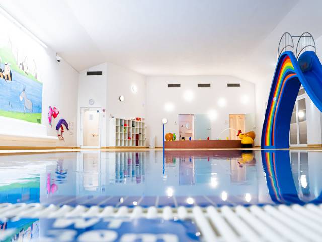 Schwimmbad mit Pool, großer bunter Rutsche und Babybereich