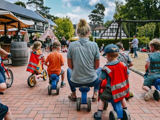 Kinderbetreuerin macht mit Kindern ein Rennen auf dem Laufrad
