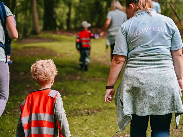 Kinderbetreuerin mit kleinem Kind spaziert durch den Wald