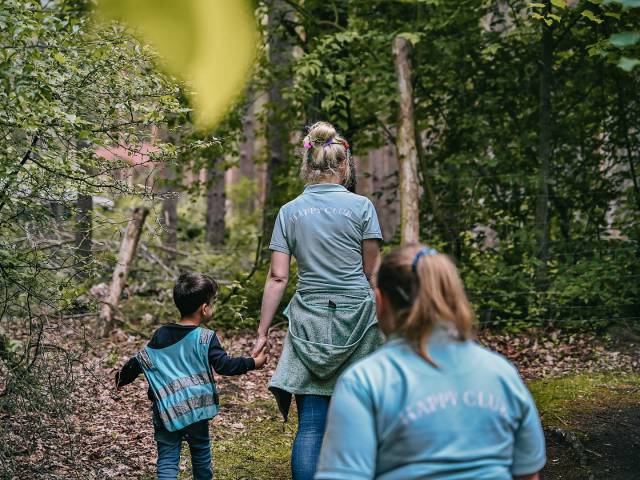 Kinderbetreuerinnen spazieren mit Kindern durch den Wald