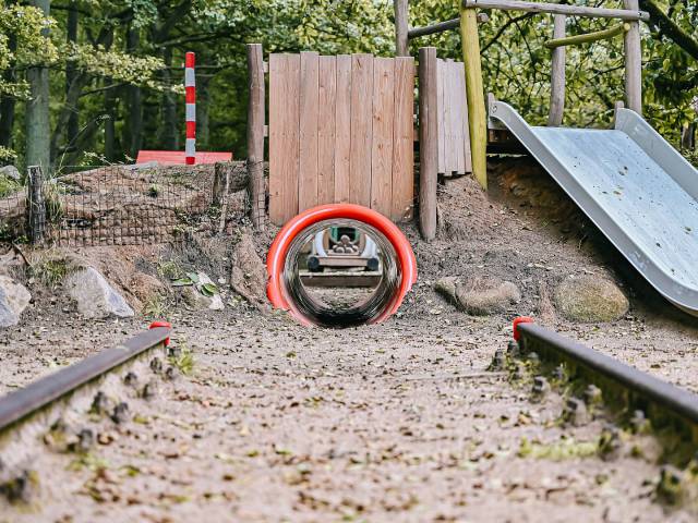 roter Tunnel über den man zu einer Rutsche laufen kann