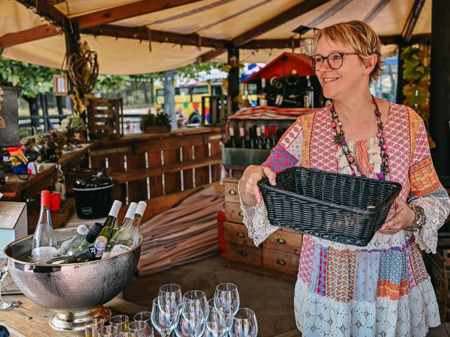 Gastgeberin Andrea im Weinprobierstand mit Korb in den Händen