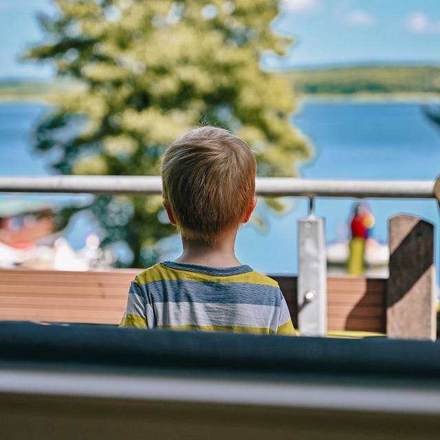 Kleiner Junge blickt auf dem Labussee auf der Terasse des Hotels