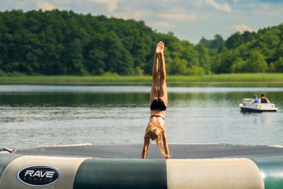 Ein Mädchen macht auf einem runden Wassertrampolin einen Handstand