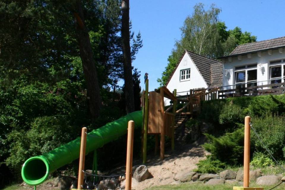 Spielplatz mit Klettermöglichkeit, grüner langer Rutsche und Balance