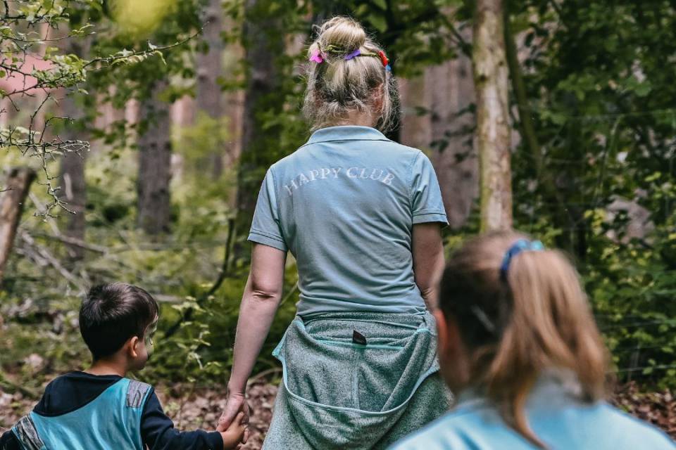 Zwei Damen der Kinderbetreuung im Wald mit einem Kind