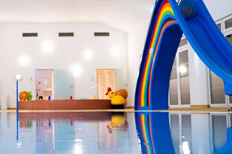 Nahaufnahme des Pools mit großer Wasserrutsche im Hintergrund und Babybecken