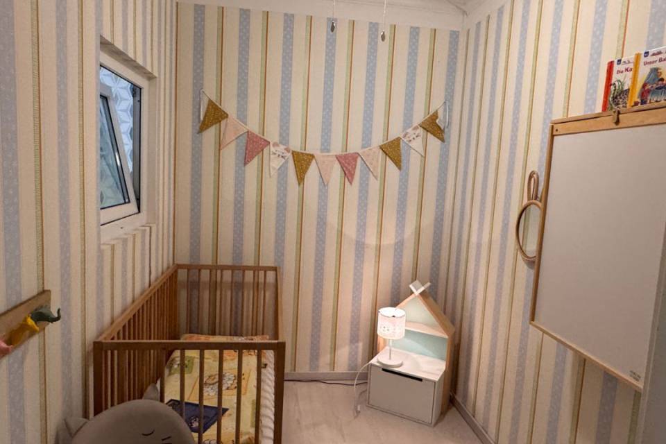 Babyzimmer im Borchards Rookhus mit Bett, Stuhl, Girlande, Wickeltisch