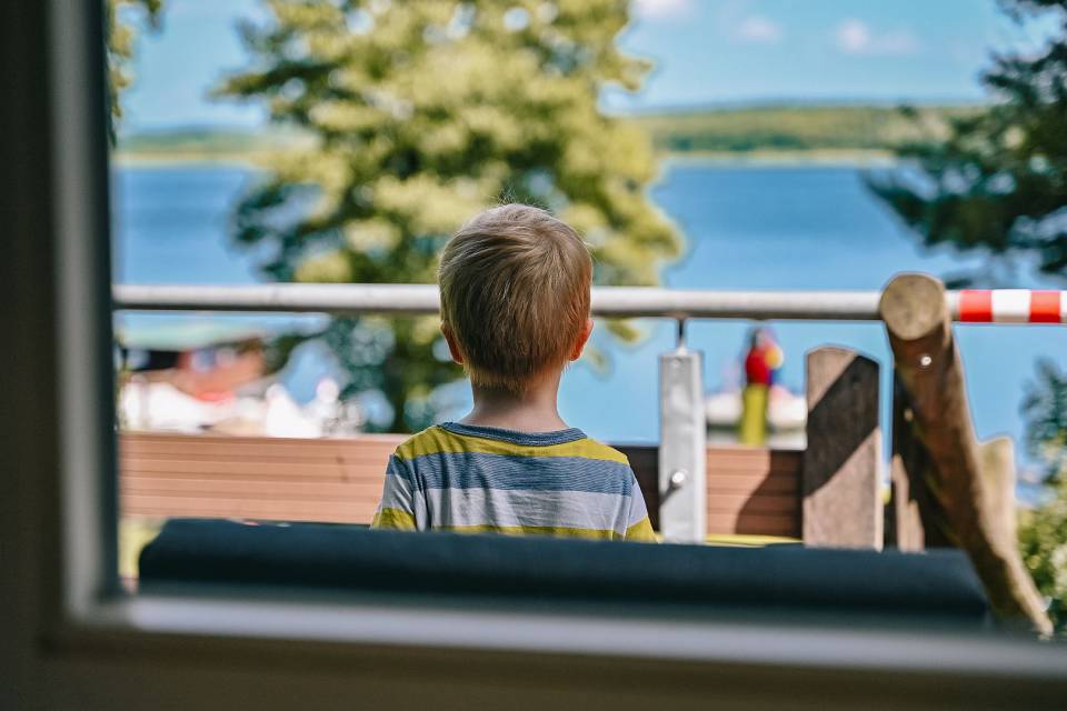 Kleiner Junge blickt auf dem Labussee auf der Terasse des Hotels