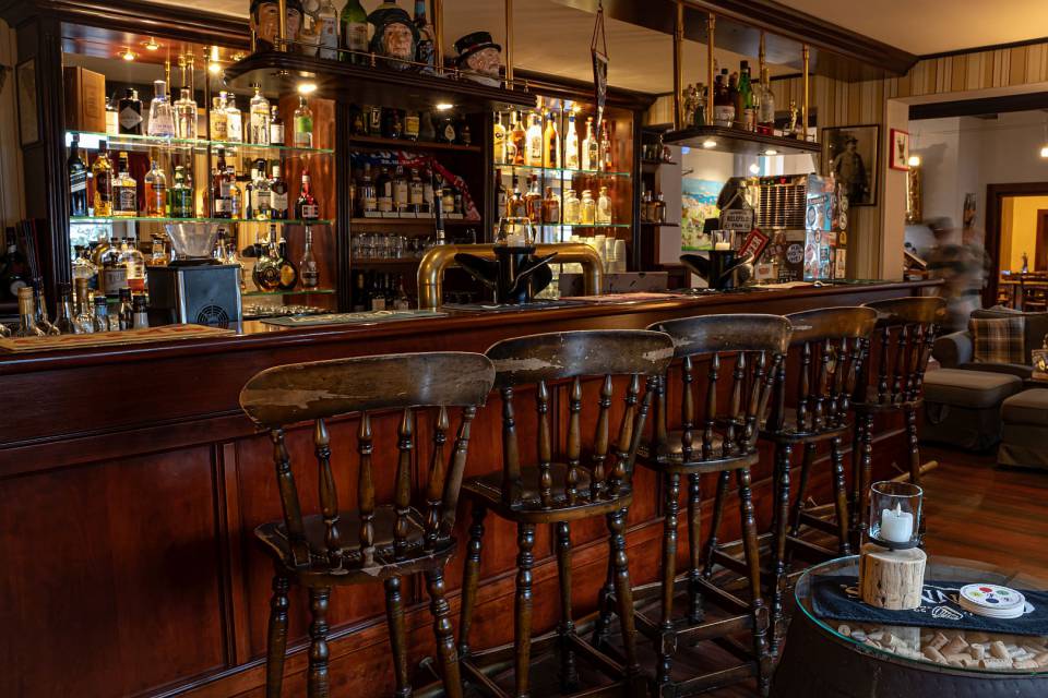 Hotelbar mit hohen Holzhockern und vielen Getrränken im alten englischen Stil
