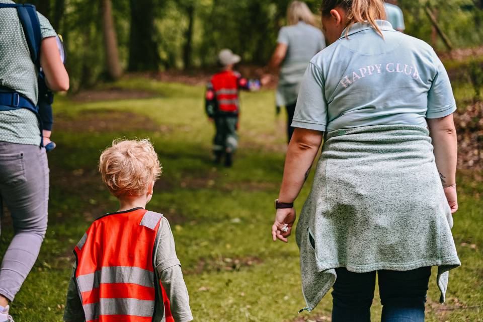 Kinderbetreuerin mit kleinem Kind spaziert durch den Wald