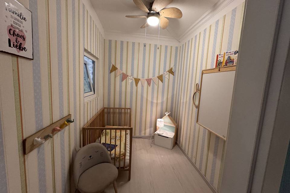 Babyzimmer mit Gitterbett, Wickelkommode und kleinem Kästchen