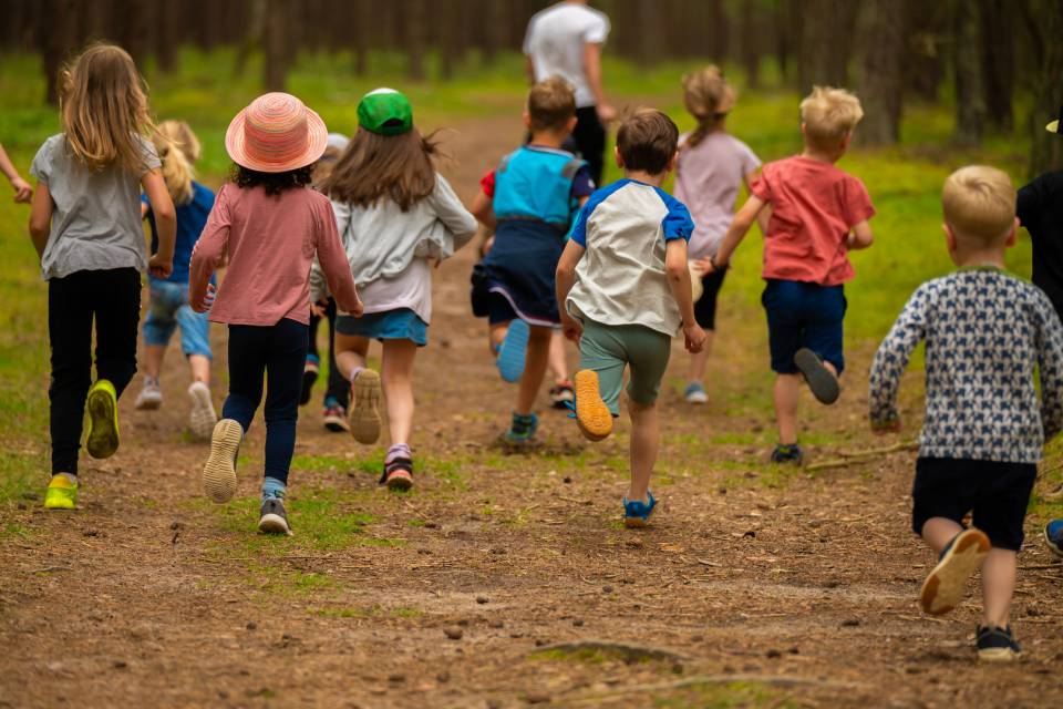 Kinder, die im Roookhus Urlaub machen, laufen durch den tiefen Wald
