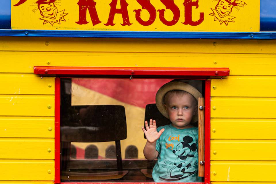 Ein Junge mit Hut sitzt in einem selbst gebauten Zirkus Kassenwagen im Rookhus