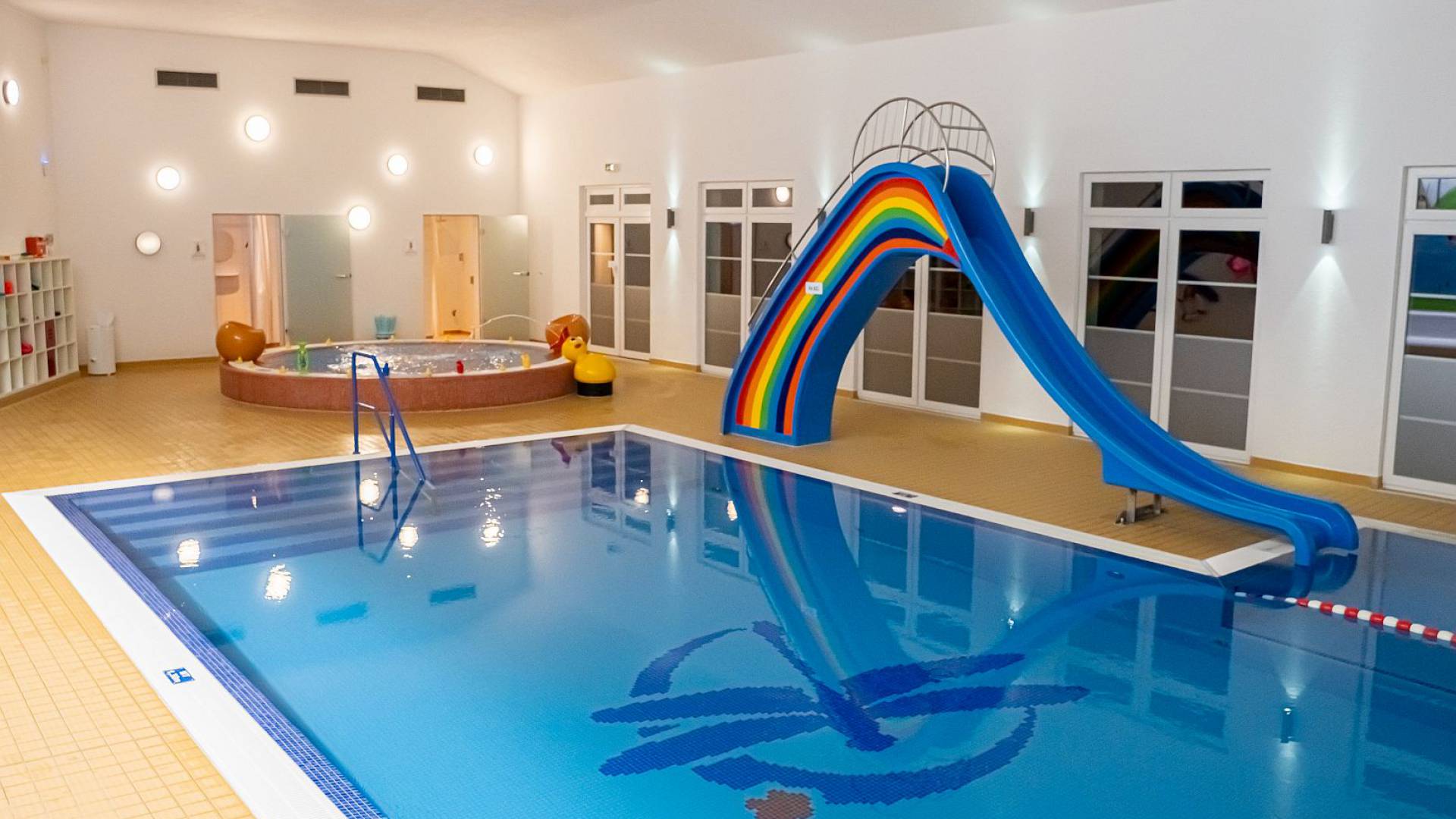 Schwimmbad, mit großer, bunter Rutsche und Babybecken im Hintergrund