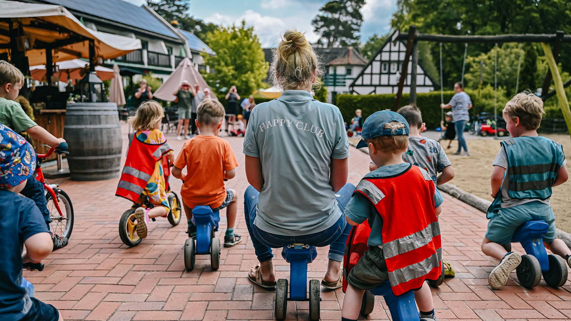 Kinderbetreuerin macht mit Kindern ein Rennen auf dem Laufrad