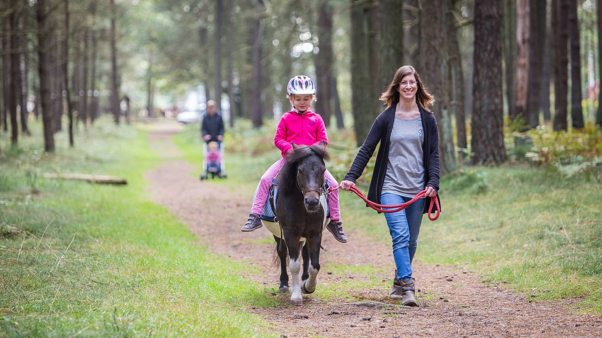 Mutter führt am Strick ein Mädchen auf dem Pony durch den Wald im Borchards Rookhus